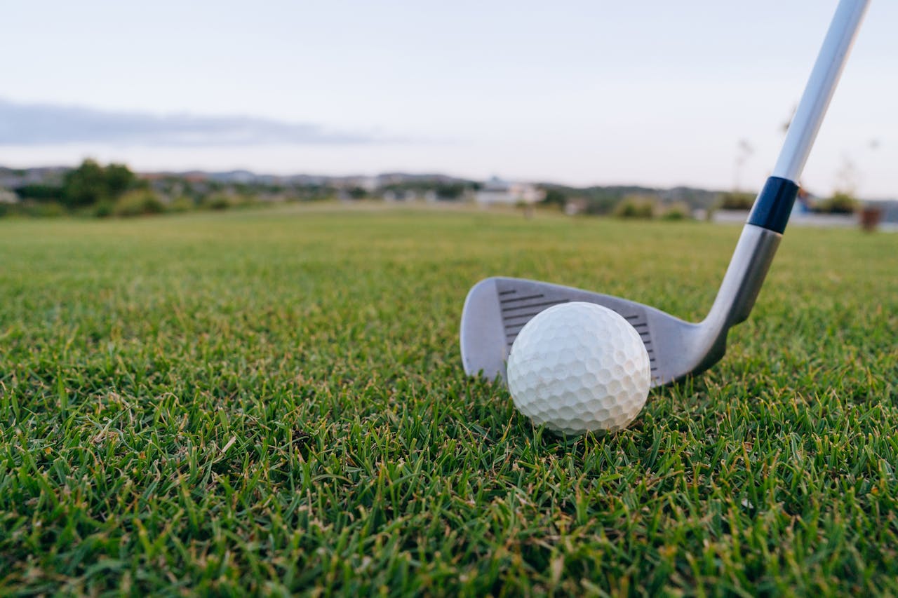 Golf ball with club on lush green grass, perfect for sports themes.